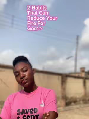 A woman in a pink t-shirt with the words "SAVED & SENT" is the focal point. The background appears to be an outdoor setting with a sky and hints of buildings and a fence. Text overlayed on the image reads "2 Habits That Can Reduce Your Fire For God>>" in pink.