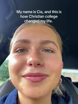 A close-up shot showing a young woman's face. The background is blurred, suggesting an indoor setting, possibly a car. The woman has fair skin, blonde hair, and is looking directly at the camera with a slight smile. Text overlayed on the image says, "My name is Cia, and this is how Christian college changed my life."