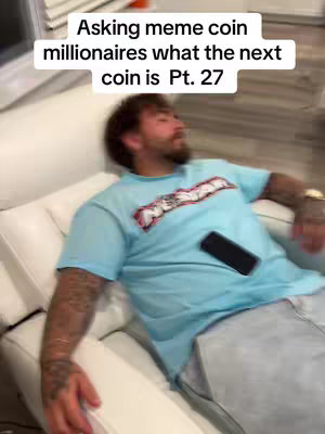 A man reclines casually on a white chaise lounge. He holds a black smartphone midair, and wears a light blue t-shirt with a logo. Text at the top says 'Asking meme coin millionaires what the next coin is Pt. 27'.