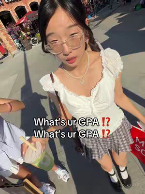 A young woman in a white top and plaid skirt, sunglasses, and a necklace, is looking at the camera. She is standing outside. Text overlays the image.