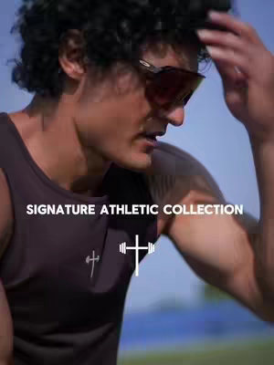 A man with curly hair and sunglasses wearing a dark tank top is the focus. Text overlay reads "SIGNATURE ATHLETIC COLLECTION". A cross graphic is centered on the tank top.