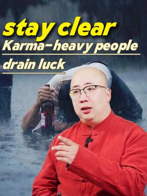 The cover image shows a man in a red shirt and glasses pointing to the right. Behind him, in a blurred background, a person is submerged in water, possibly in a rainstorm, with their face hidden. The text 'stay clear Karma-heavy people drain luck' is overlaid in yellow and white fonts across the top.