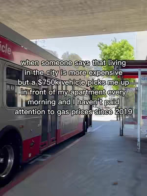 A city bus is the main focus of the image. Text is overlaid on the image. The bus is silver and red, and is parked next to a bus stop.