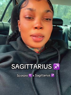 A woman with dark hair is seen from the chest up, positioned within a car. She's wearing a black hoodie. Text overlays identify her astrological sign as Sagittarius and mentions an astrological pairing.
