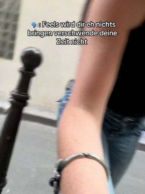 The image features a close-up of a person's arm and a portion of their torso, likely in an outdoor setting, with a dark-colored top and jeans. A decorative silver bracelet is visible on the wrist. The background is blurred, suggesting a shallow depth of field, and the text overlay indicates emotional content.