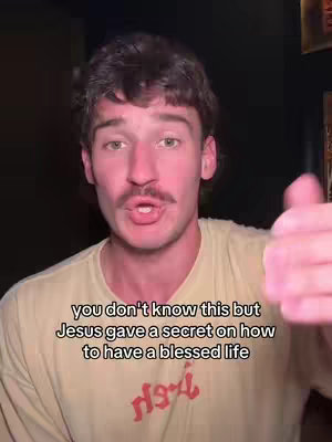 A man with a mustache and short hair, wearing a yellow shirt with a red logo, is speaking directly to the camera. Text overlays are visible at the bottom, indicating a religious theme.