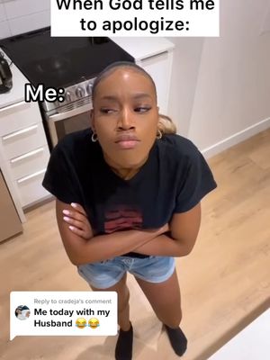 A woman stands in a kitchen, looking up with a slightly annoyed expression, arms crossed. The background shows a modern kitchen with appliances and wooden floors. Text overlays read "When God tells me to apologize:" and "Me:". A comment box with text "Me today with my Husband" is near the bottom with emoji reactions.