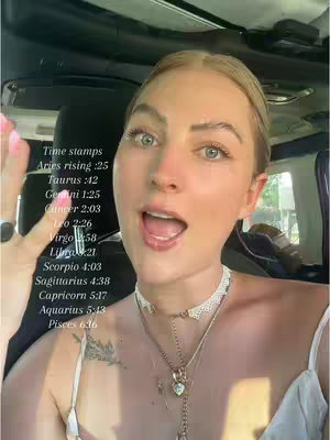 A woman with blonde hair and light makeup has her mouth open in an expression of surprise or excitement. Text overlay on the image includes a list of astrological time stamps. She is wearing a white lacy necklace against a light-colored top and has a tattoo visible on her shoulder.