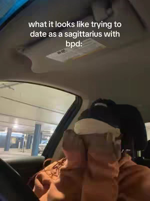 The image shows a person inside a car, apparently filming from the driver's seat with the camera pointed towards their face, but only their hands are covering their face. The background looks like a parking garage. Text overlay across the top says "what it looks like trying to date as a sagittarius with bpd:"