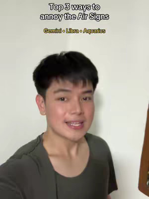 A young man with short black hair and a dark green t-shirt is centered in the frame. Text overlays at the top of the image announce "Top 3 ways to annoy the Air Signs", followed by the sign names Gemini, Libra, and Aquarius. The background is a plain off-white wall, creating a minimalist composition.