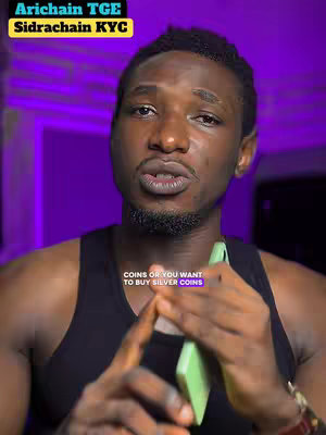 A selfie-style video shot with a man centered in the frame. He has short, dark hair and is wearing a black tank top. He has a serious expression, looking directly at the camera with his mouth slightly open as if speaking. The background is a diffused purple, suggesting studio lighting. In the lower portion of the image, there is overlaid text.