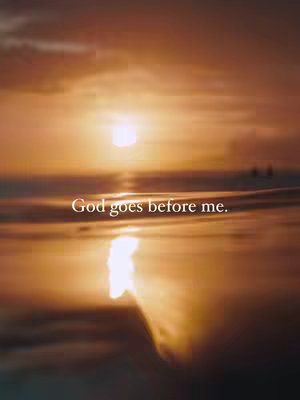 A serene image of a sunset over the ocean. The sky is filled with warm orange and yellow hues, with the sun barely visible through the clouds. The ocean reflects the colors of the sky, and the text "God goes before me." is displayed in a clean white font.