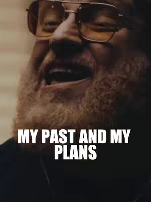 A close-up shot of a man with a beard and sunglasses appears to be captured in partial silhouette. The man, with a slightly open mouth, appears to be speaking or singing. Text overlay, 'MY PAST AND MY PLANS', is visible below him.
