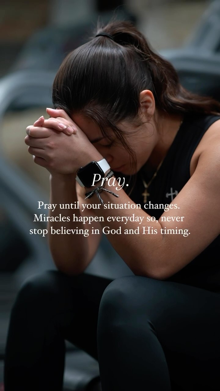 A woman with dark hair is seated with her head bowed, hands clasped in prayer. She is wearing a black top and watch. Text overlays read 'Pray' and a motivational quote. The background is blurred, suggesting an indoor setting, possibly a gym.