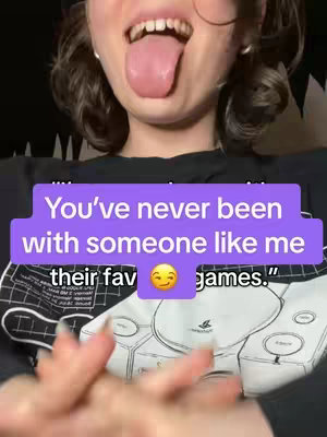 A selfie-style image featuring a person sticking out their tongue with a graphic overlay. The background is blurred, but appears to be indoors, with a hint of a black garment on the subject and a grey design on a sweatshirt below. The text overlay has a purple background and white text.