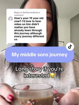 The cover image is a selfie-style shot of a woman holding a coffee cup. The background is neutral, suggesting an indoor setting likely a home. The woman has black hair, dark eyes, and wears a cream-colored sweater. Her nails are painted red. Overlaid on the image is a speech bubble with a comment from another user. Beneath the comment is a light blue label indicating the title 'My middle sons journey'. The text 'Long story if you're interested 😂' is placed below this label, adding a casual tone. A TikTok logo is floating on the top right corner to indicate source.