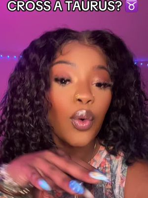 A close-up shot of a woman with long, curly black hair. The woman has a nose ring, and her lips are glossed. There's overlaid text at the top reading 'CROSS A TAURUS?' with a Taurus zodiac symbol. The background features a gradient of pink and purple.