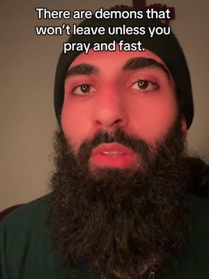 A close-up shot of a man with a beard wearing a beanie. The man's facial features are illuminated by a red light. Text overlay at the top reads: "There are demons that won't leave unless you pray and fast."