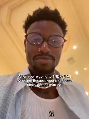 A man with dark skin, wearing glasses and a white shirt, stands in front of a blurry background. Text overlayed on the image says 'When you're going to THE ROYAL wedding! Because your friends are finally getting married'.