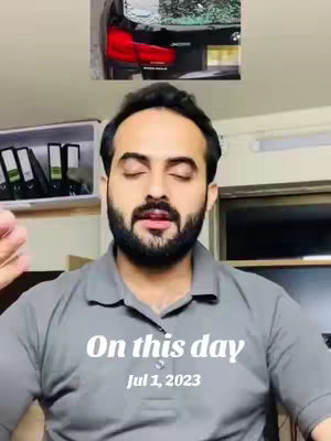 A man with a dark beard is the focal point, positioned in front of a neutral indoor setting, against a backdrop of what appears to be a car or a vehicle's rear, placed at the top-center of the frame. The man is wearing a gray polo shirt and has his eyes closed. Overlayed text at the bottom of the image reads "On this day Jul 1, 2023."