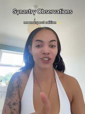 A selfie-style video cover image featuring a woman in a white halter top. The background appears to be an indoor setting with a window visible, possibly a living room. Text overlays at the top of the image read: 'Synastry Observations' and 'moon aspect edition' . The woman is looking directly at the camera and appears to be speaking.