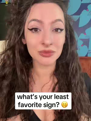 A young woman with long, wavy brown hair and makeup is centered in the frame. She is looking directly at the camera with a neutral expression. A white rectangular text box is at the bottom of the screen containing the words: "what's your least favorite sign?" There is an emoji of a face with a rolling eye next to it.