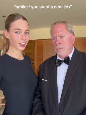 A woman in a black dress smiles next to an older man in a suit with a bow tie. Text at the top says "smile if you want a new job".