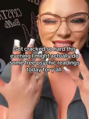 A close-up shot features a woman with a fair complexion, wearing large, neutral-toned glasses, and a dark top. Her hands are raised and in front of her, showcasing long, well-manicured nails. The background is blurred but it is possible to see a logo of sorts on the top. Text is added overlayed at the bottom of the main focus.