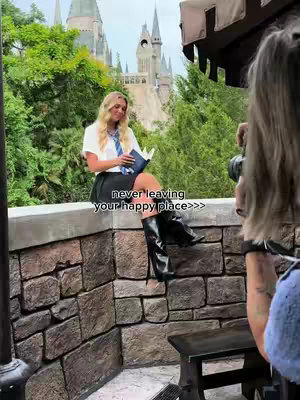 A woman with blonde hair, wearing a Harry Potter-themed outfit, sits on a stone wall. Behind her is a backdrop of the Hogwarts castle. Another person is taking a photo from the right side of the frame. Text is overlaid on the image.
