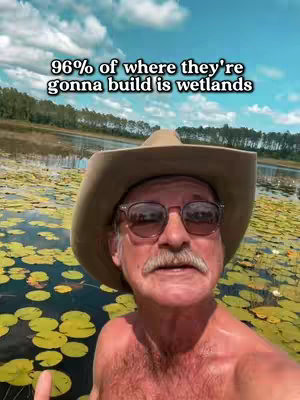 The image shows a man with sunglasses and a hat standing in front of a body of water with lily pads. Text overlays the image stating '96% of where they're gonna build is wetlands'.