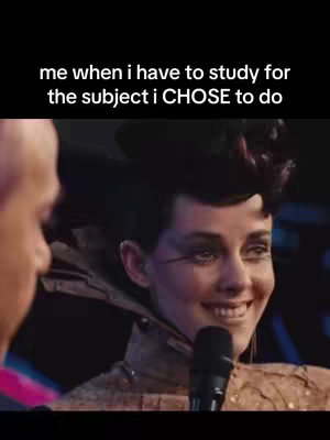 A cover image featuring a scene from a movie. The main subject is a woman smiling while holding a microphone, likely addressing an audience. She is dressed in costume with dark hair styled up. Text is overlaid at the top as a hook: “me when i have to study for the subject i CHOSE to do”. The background appears to be an event stage of some kind.