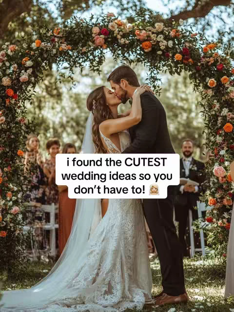 A romantic wedding scene featuring a kissing couple under a floral archway. A bride in a white dress with a veil and a groom in a black suit kiss. They are surrounded by guests at an outdoor venue with lush greenery and a flower arch. Text overlay adds a hook for wedding ideas.