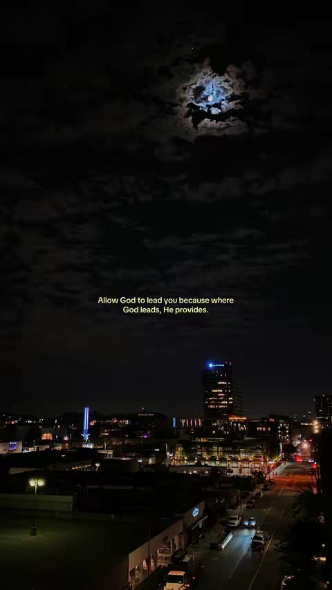 A night scene with a cityscape at the bottom and the night sky above. In the sky, the moon is partially obscured by clouds, and text is overlaid, conveying the message of faith and guidance. The scene is lit by street lights and the lights of the buildings.