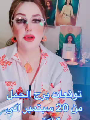 A woman with makeup and glasses is centered in a medium shot. Behind her are framed pictures. The main elements are the woman herself and the text overlay about Aries predictions starting September 20th thru October 1st.