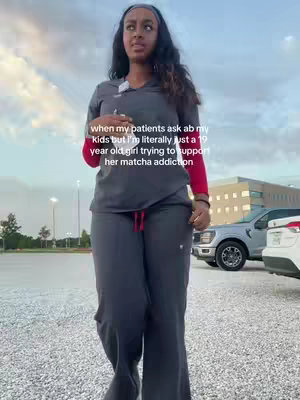 A woman in grey scrubs stands in the center, facing the camera. The background shows a parking lot, a building, and a cloudy sky. Text overlay indicates the woman is a healthcare professional often questioned about her kids but is only 19 years old.