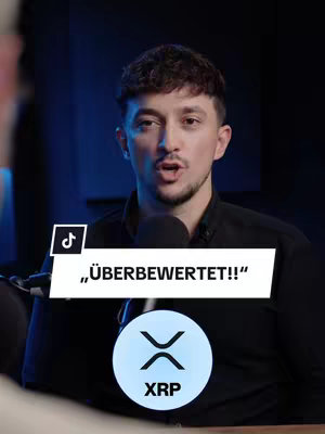 A man speaking in front of a microphone with a blue and black background. overlaid with a TikTok logo, a white text box that reads "ÜBERBEWERTET!!" in bold text, and a circular graphic with the letters "XRP" below a logo.
