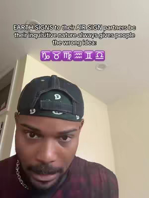 The cover image shows a head and shoulders shot of a Black man looking toward the camera with a neutral expression. The man is wearing a black baseball cap and a chain necklace. White text at the top of the frame poses a question regarding earth signs and air signs. Below the text are zodiac symbols representing various signs.
