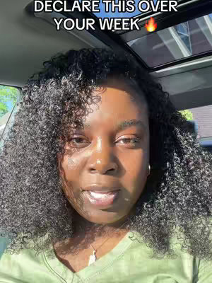A woman with dark curly hair is sitting in a car, looking directly at the camera. Text overlayed on top says "DECLARE THIS OVER YOUR WEEK". The background shows a sunny environment, suggesting it's daytime.