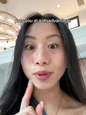 A close-up shot of a young woman with long black hair and fair skin. She has her mouth slightly open and is pointing her index finger towards her cheek. Text overlayed reads 'puts you at a disadvantage'.