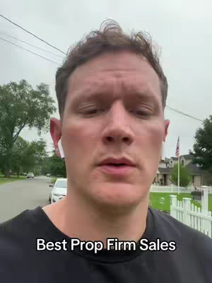 A man stands outside, the camera pointed at him. He is wearing a black shirt and white earbuds. The background shows a residential street with some houses. Text overlay in the lower section says "Best Prop Firm Sales".