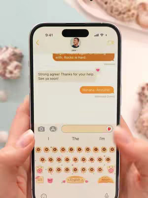 A person using a phone that is displaying a custom keyboard with many different font and keyboard skin options. The background appears to be a light-colored, stylized setting with bokeh effects. The person is holding the phone with their hands.