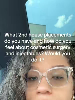 A selfie-style video with the creator partially visible, framed from the forehead down. The creator wears clear-framed glasses and is looking slightly to the side, with curly hair framing the face. The background shows a car interior with a blue sky visible through the window.