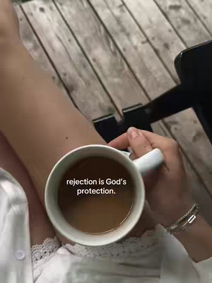 The cover image presents a first-person perspective with a woman holding a white mug filled with a light-brown liquid. The mug is held over her legs, partially covering the white lace trim of her top and her visible forearm, which is adorned with a bracelet. The background suggests a wooden deck, adding an outdoor element to the shot. Text is overlaid on the mug's contents, creating direct communication with the viewer.