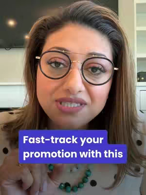 A woman with brown hair and glasses is centered in the frame, with a blurred background. A blue rectangular text overlay is placed at her center. She's wearing a light-colored top and a beaded necklace. Her expression is serious, lips slightly parted as if speaking.