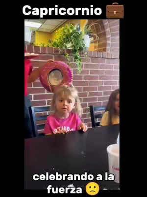 The cover image captures a young girl sitting at a table. She appears unimpressed or perhaps resigned, with a Mexican-style hat being held over her head and other blurry people in the background. The setting looks like a restaurant, with a brick wall and a sign visible.