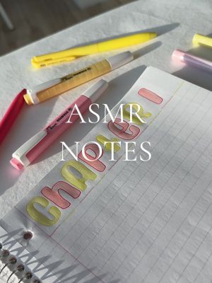 An overhead shot of a notebook with grid paper, partially filled with handwritten notes highlighted in yellow and pink. Several pens and highlighters are scattered around the notebook, and the words "ASMR NOTES CHAPTER 1" are written in bold, stylized letters on a piece of paper pasted on the grid paper.