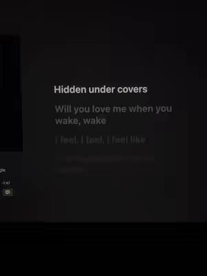 A dark screen displays song lyrics with white text, including phrases like 'Hidden under covers' and lines of verse. There's a blurred image on the left side, likely from an app interface, and the overall composition is simple and text-focused.
