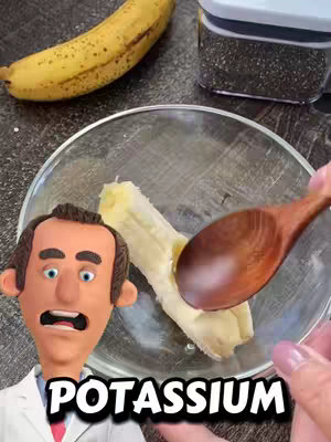 The image shows a close-up of a glass bowl with a split banana being scooped with a wooden spoon by a hand and a cartoon of a man with a shocked face on the left, with the word POTASSIUM in bold white block letters below