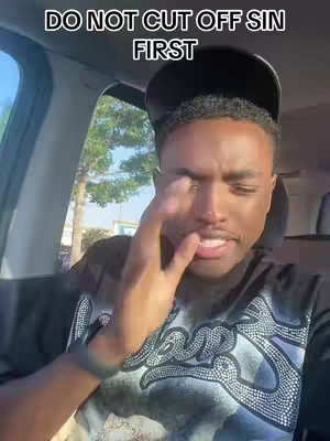 A man in a car interior is looking down towards his fingers near his face and mouth with a serious expression. Above his head is a text overlay that says, "DO NOT CUT OFF SIN FIRST".