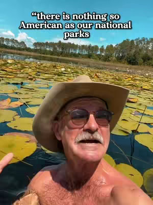 A man wearing a cowboy hat and sunglasses is standing in water covered in lily pads, with a background of trees and a blue sky. Text overlay at the top reads a quote.